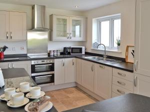 una cocina con armarios blancos y encimeras negras en Grey Cottage, en Pentraeth