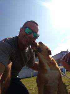 a man with sunglasses on is kissing a dog at CASA PRAIA PINHEIRA e GUARDA EMBAU in Palhoça