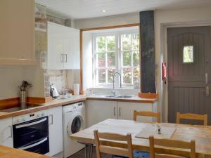 een keuken met een tafel, een wastafel en een raam bij Pear Tree Cottage in Wirksworth