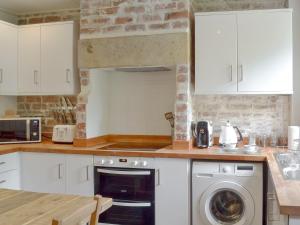 Pear Tree Cottage في Wirksworth: مطبخ مع دواليب بيضاء وغسالة صحون