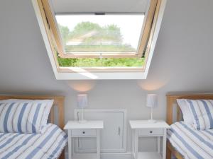 two beds in a room with a window at Pear Tree Cottage in Wirksworth