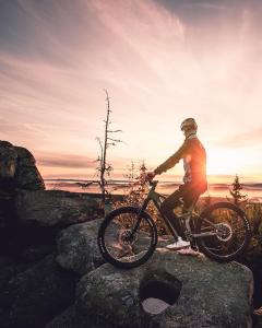 a person riding a bike on a rock at sunset at Chalet-Ferienwohnung Sonnenidyll, 51 qm, Wellness/Fitness/Sauna – Bergrödelhof in Feilitzsch