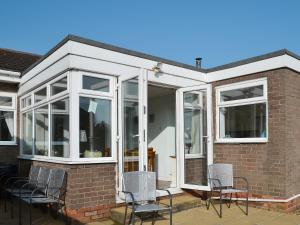 a conservatory with white windows and chairs on a house at 61 Longstone Close in Beadnell