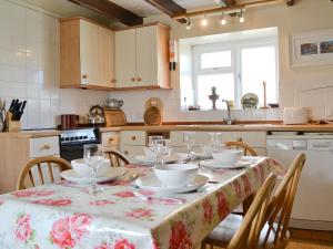 una cocina con una mesa con platos y vasos. en Trem-y-don Cottage, en Trevine