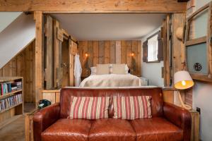 a leather couch in a room with a bed at The Cowshed at Cheshire Boutique Barns in Nantwich