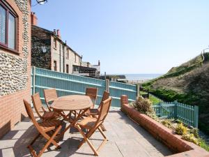 a table and chairs on a patio with the ocean at Beach Retreat - E5558 in Mundesley