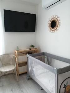 a bedroom with a crib and a tv on the wall at PortStreet apartamenti in Liepāja