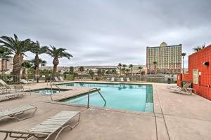 a pool with chairs and palm trees and a building at Step-Free Bullhead City Condo with Balcony! in Bullhead City