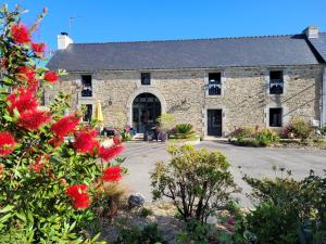 a stone building with red flowers in front of it at La Maison Keribin in Moëlan-sur-Mer