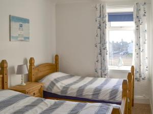 a bedroom with two beds and a window at The Lobster Pot in Amble