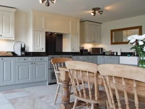 uma cozinha com armários brancos e uma mesa e cadeiras em Mortar Barn em Stainsacre