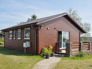 a small wooden cabin with a large window at Hawthorne in Woolfardisworthy