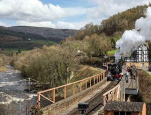 a steam train is coming down the tracks at Berwyn Stationmasters House - Hw7641 in Llangollen