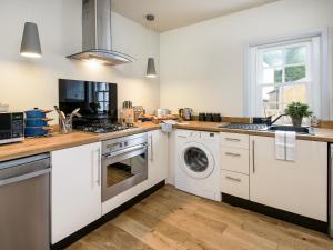 a kitchen with white cabinets and a washer and dryer at Knocktinkle in Gatehouse of Fleet