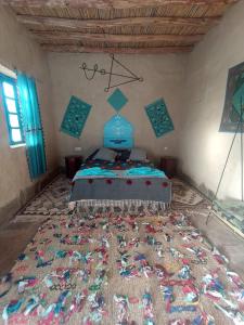 een slaapkamer met een bed met een tapijt op de vloer bij Dar Oasis Moringa in Merzane