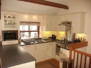 uma cozinha com armários brancos e um forno com placa de fogão em Applecroft em Keswick