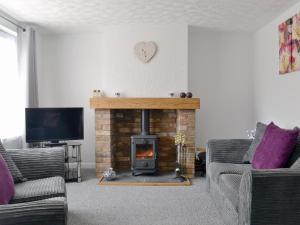 a living room with a fireplace and a tv at Banovallum Cottage in Horncastle