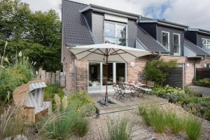 a patio with an umbrella in front of a house at Ferienhaus DHH SKILLEHUS in Tating