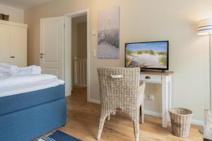 a bedroom with a bed and a desk with a television at Ferienhaus DHH SKILLEHUS in Tating