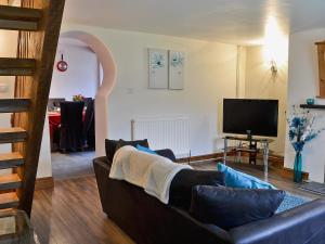 a living room with a couch and a television at Bont Cottage in Kidwelly