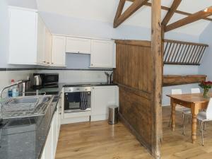 a kitchen with white cabinets and a wooden wall at Ingleby Barn - 27946 in Battersby