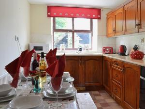 a kitchen with a table with wine bottles and glasses at Ty Coch Cottage in Dihewid