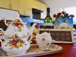 stół z 2 zestawami do herbaty i butelką wina w obiekcie Ellen Cottage w mieście Ireby