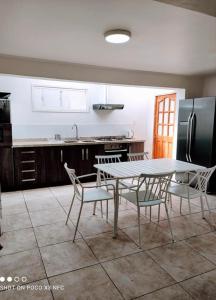cocina con mesa, sillas y nevera en Santa Teresa Hostel, en Temuco