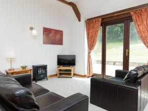 a living room with a couch and a television at Bramble Cottage in Radstock