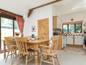cocina y comedor con mesa de madera y sillas en Bramble Cottage, en Radstock