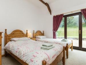2 Betten in einem Schlafzimmer mit Fenster in der Unterkunft Bramble Cottage in Radstock