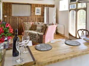 sala de estar con mesa de madera y copas de vino en Evie Rose Cottage, en Elsenham