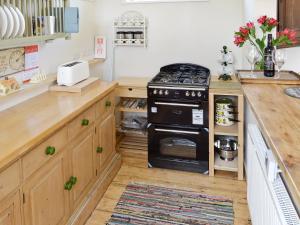 a kitchen with a black stove and wooden cabinets at Evie Rose Cottage in Elsenham