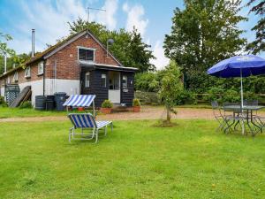 un patio con mesa, sillas y sombrilla en Evie Rose Cottage, en Elsenham
