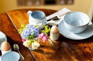 una mesa de madera con huevos y flores y dos tazas en Meadow Barn, en Axminster