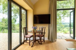 a dining room with a table with chairs and a television at Meadow Barn in Axminster