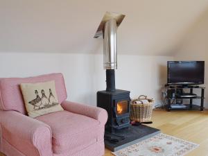 sala de estar con silla rosa y fogones en Mill Cottage, en Comrie