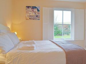 ein weißes Bett in einem Zimmer mit Fenster in der Unterkunft Mill Cottage in Comrie