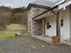 Casa blanca con porche con maceta en Mill Cottage, en Comrie