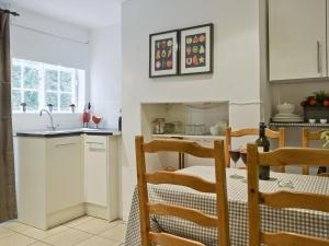 a kitchen with white cabinets and a table and chairs at Hill View Cottage in Snowshill