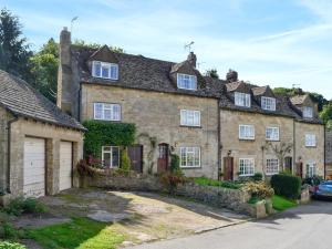 an old stone house with a garage in front of it at Hill View Cottage in Snowshill