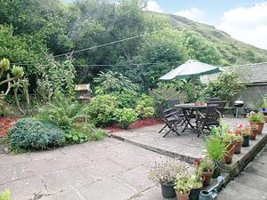a garden with a table and chairs and potted plants at Braemar in Lendalfoot