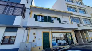 un edificio blanco con puerta verde y balcón en Casinha do Rui, en Sines