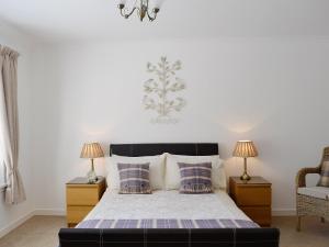 a bedroom with a bed with two lamps and a chair at Song Bird Cottage in Lochend