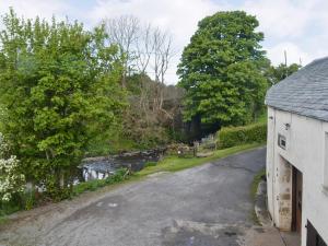 an empty road next to a river with a house at The Corn Mill in Branthwaite