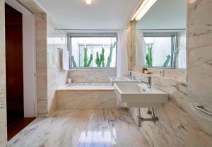 a bathroom with two sinks and a tub and a window at Hotel Porto Santo & Spa in Porto Santo