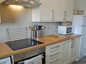 a kitchen with white cabinets and a white microwave at Sandy View in Beadnell