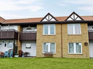 a large brick house with a grass yard at Sandy View in Beadnell