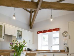 a kitchen with white cabinets and a window at The Coach House in Whittingham