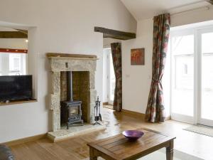 a living room with a fireplace and a table at The Coach House in Whittingham